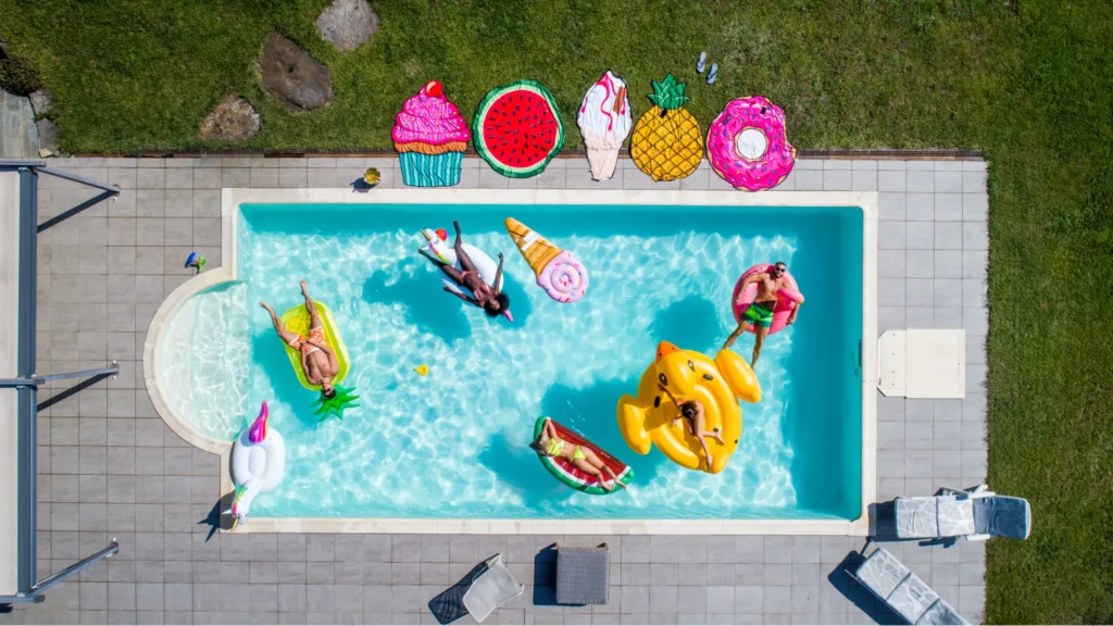 Top-down view of people in pool with colorful pool floaties surrounding
