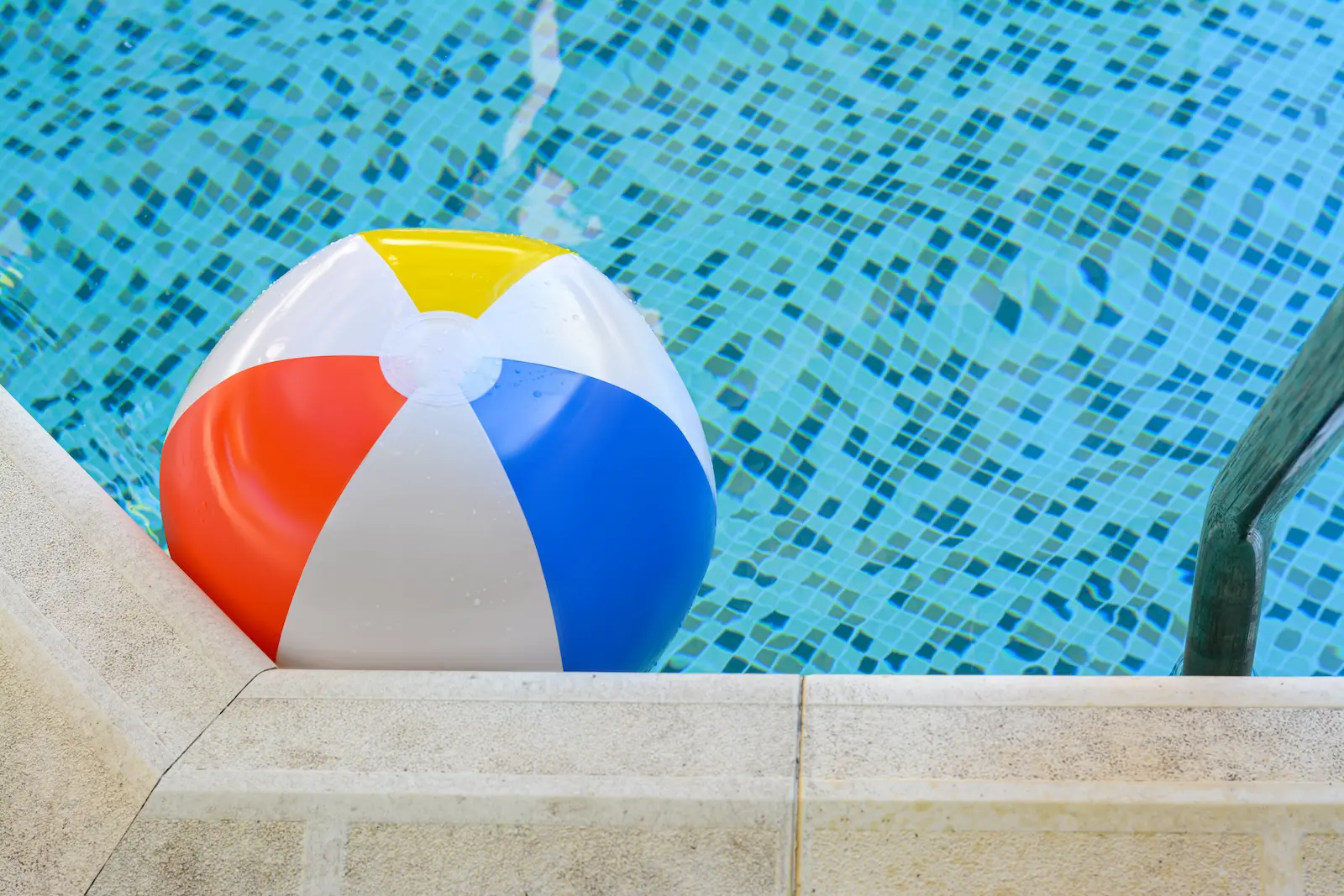 Beach ball floating near swimming pool's edge